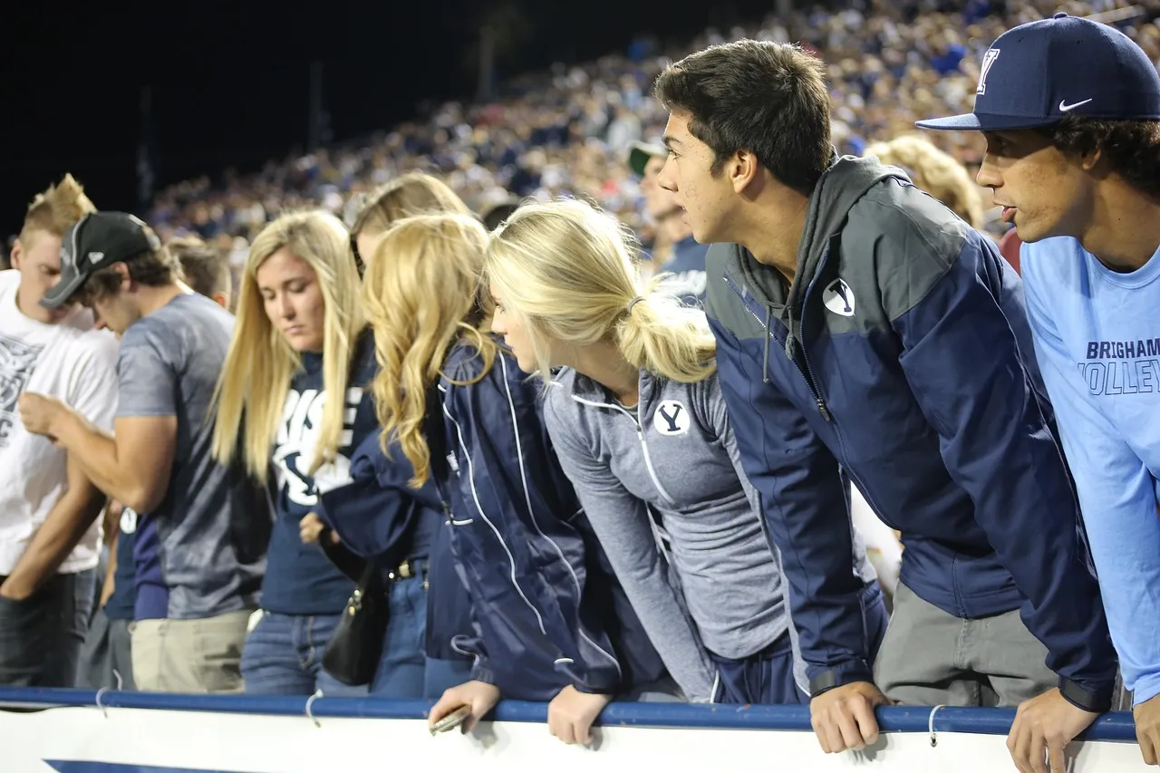 Fans in the stands of a football stadium in the evening