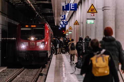 Pasażerowie czekający na pociąg na peronie stacji kolejowej