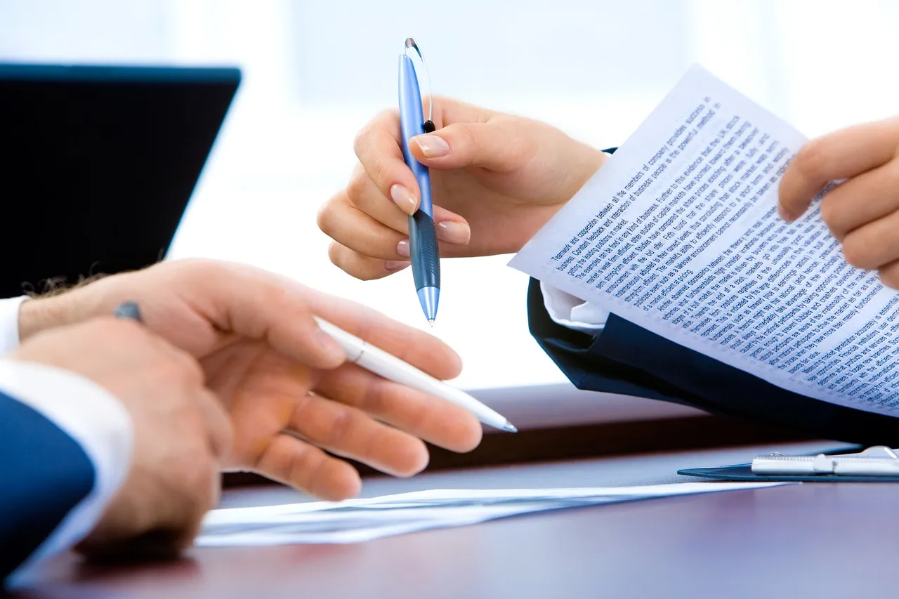 Person filling in documents on a laptop in an office