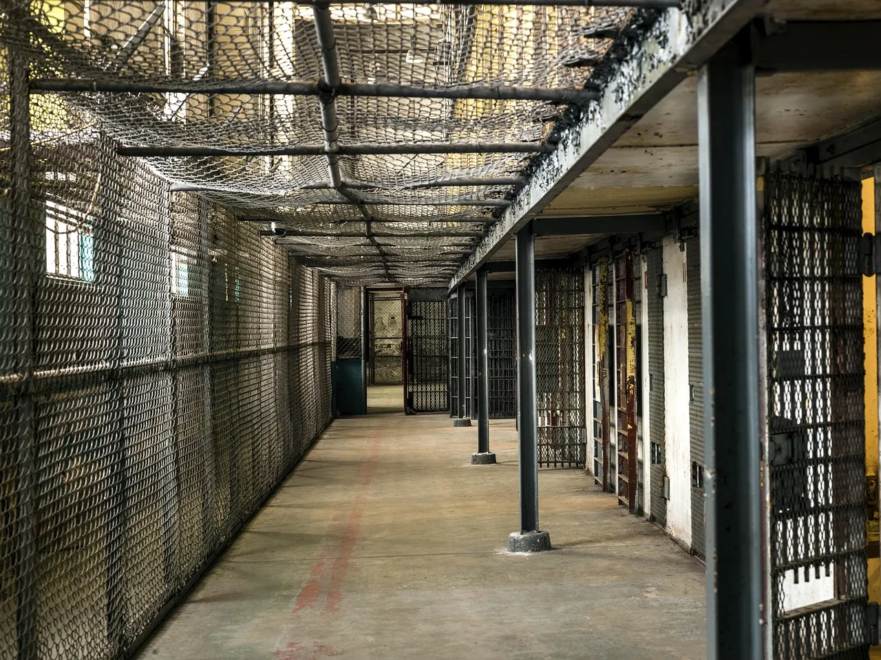 An empty prison corridor lined with cells