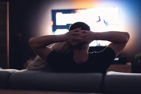 Osoba oglądająca serial w telewizji na kanapie