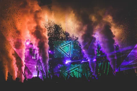 Scena koncertowa z laserami i światłami podczas występu muzyki elektronicznej