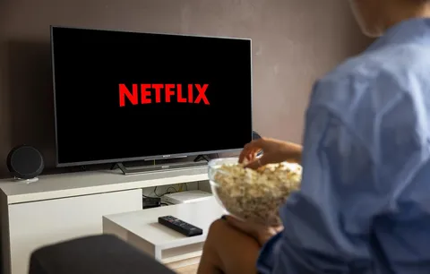 Osoba oglądająca serial na ekranie telewizora wieczorem