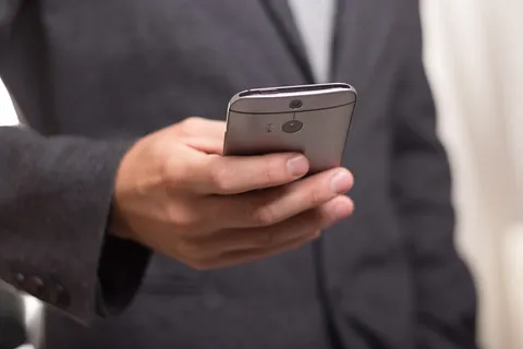 Osoba trzymająca smartfon z podejrzaną wiadomością