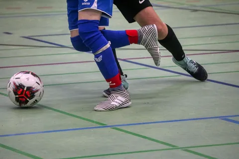 Zawodnicy walczący o piłkę podczas meczu futsalu w hali