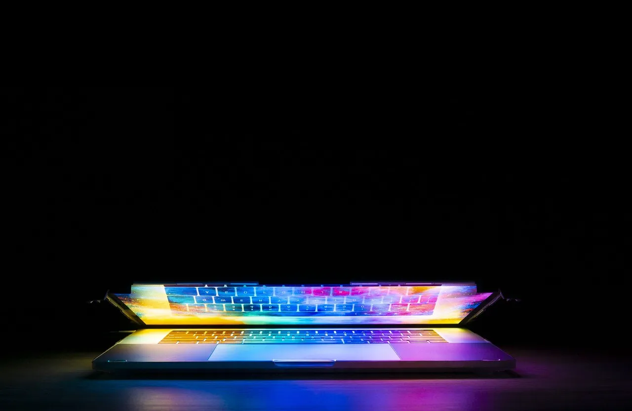 A person at a computer keyboard in a dark room