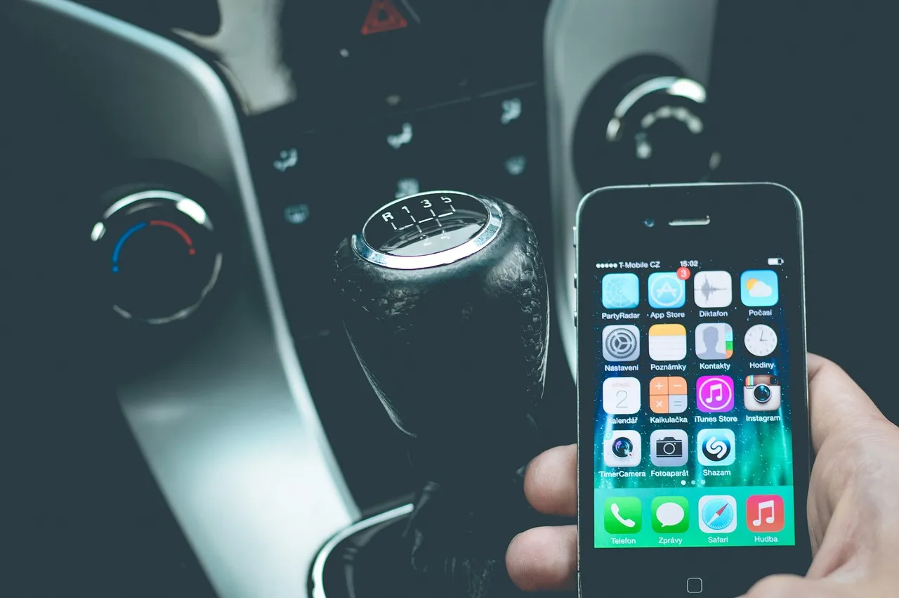 A driver using a smartphone next to a car