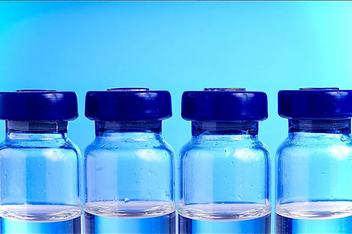 A row of four glass vials with blue caps against a blue background