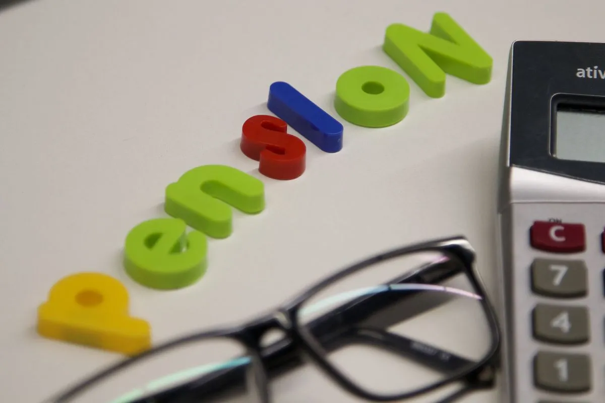 Colourful letters spelling the word pension next to a calculator and glasses on a white desk