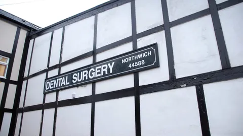 Biała fasada z czarnymi belkami szachulcowymi i ciemnym szyldem z napisem Dental Surgery Northwich