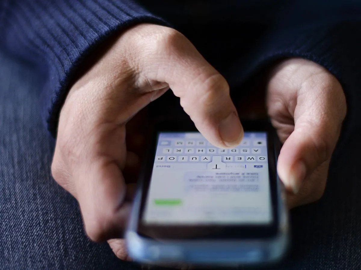 Hands holding a smartphone with a text conversation and the keyboard open on the screen