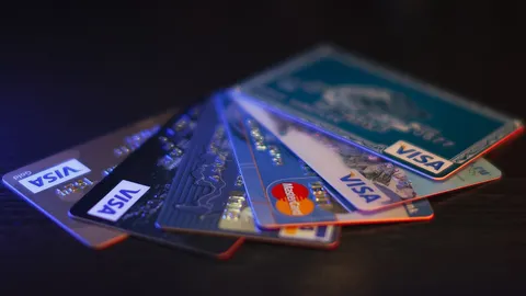 Rozłożone w wachlarz karty płatnicze Visa i Mastercard leżące na ciemnym blacie