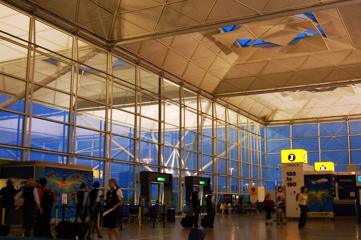 Przeszklona hala terminalu lotniska Stansted z podróżnymi przy stanowiskach odprawy